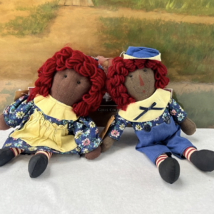 Vintage African-American Raggedy Ann and Andy dolls by Springford with red yarn hair, floral outfits, and striped socks sitting side by side.